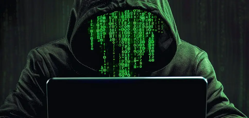 Hacker en hoodie devant un ordinateur avec du code vert pour illustrer une cyberattaque Cryptolocker.